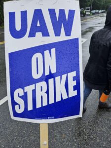 A white and blue picket sign that reads "UAW ON STRIKE"